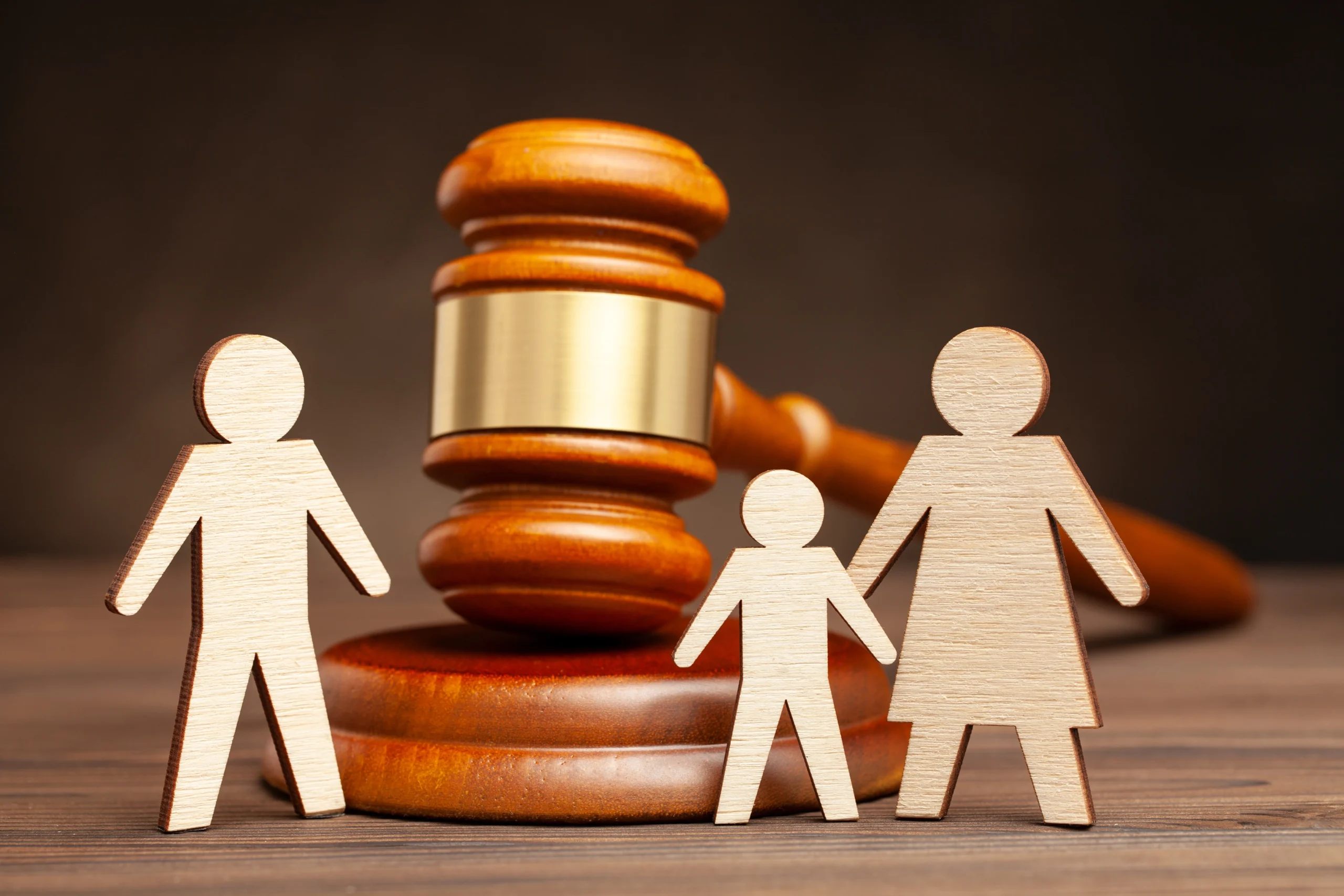 Family law concept with wooden parents and child figures in front of a judge’s gavel.